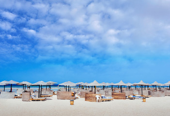 Empty beautiful clean beach with sunbeds and umbrellas, Egypt. Vacation concept. View of the beach with umbrellas and palm trees