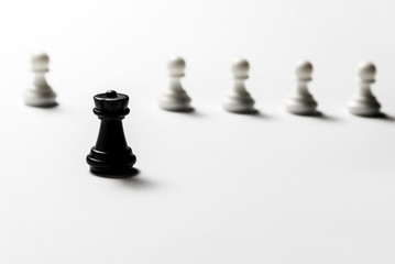 Chess black rook stands against white pawns. Symbol of leadership and confrontation. Horizontal frame