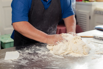 Male hands preparing dough - Hispanic adult man kneading dough to make bread - close up of raw dough