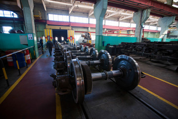 Axles with wheels of railway cars lie in a row at a repair plant