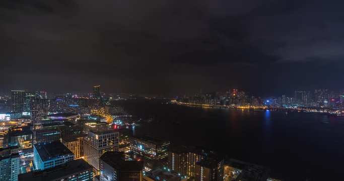 Hong Kong China, night cityscape time lapse from observation deck of tall hotel on mainland facing island. Includes 4 clips - the same view from 2 different days + panning versions of the 2 shots.