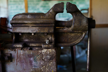 Old rusty steel clamp vise iron metal tool in the workshop workbench in day side view
