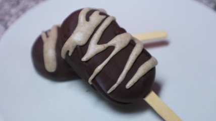 Dos helados de chocolate con rayas de chocolate blanco en un plato blanco