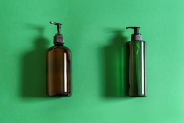Fototapeta premium Green plastic cosmetic bottle and brown glass bottle and on green paper background natural light 