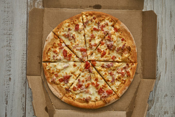 Pizza assorted pepperoni in a box and on a white plate. Fresh hot pizza with cheese and seafood.