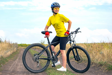 Fototapeta na wymiar Beautiful girl cyclist with a bicycle on the nature. Healthy lifestyle and sport. Leisure and hobbies