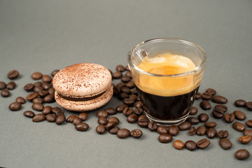  close up of coffee mug scattered coffee beans and  macaron cookies