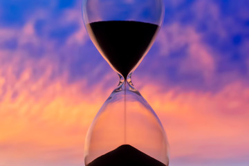 Hourglass on the background of a sunset sky. The value of time in life. An eternity.