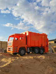 Orange toy truck on the sand in construction site