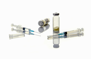 Medical syringe with an injection needle, a bottle of medicine on a medical table.