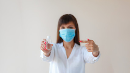 Caucasian young woman wearing protective respiratory mask using alcohol antiseptic gel for prevent infection. Medical concept protection from outbreak Covid 19 virus, cold, flu, respiratory disease.