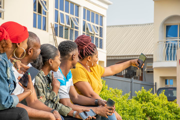 group of young african friends hanging out together outdoors, having fun, taking selfies