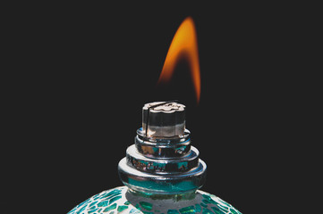 Ignited catalytic turquoise lamp against the black background. Flame concept, burning lamp. 