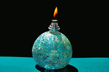 Ignited catalytic turquoise lamp against the black background. Flame concept, burning lamp. 