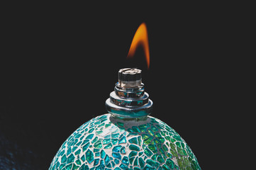 Ignited catalytic turquoise lamp against the black background. Flame concept, burning lamp. 