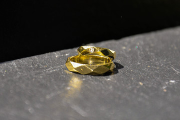 Two well designed golden wedding rings with scratches on the grey stone background. Marriage concept.