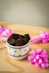 cup with chocolates with pink artificial flowers