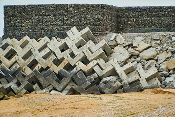 Breakwaters stand on the sea shore near the stone wall. The lattice of concrete.