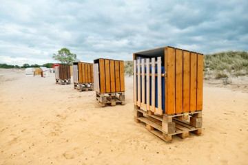 4 beach chairs, home made from wooden boards and Euro pallets, are on the Baltic Sea beach in...