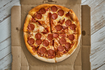 Pizza assorted pepperoni in a box and on a white plate. Fresh hot pizza with cheese and seafood.