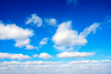 Spring azure sky with white fluffy clouds on a blue background