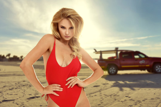 Beautiful girl in red bathing suit lifeguard on white beach
