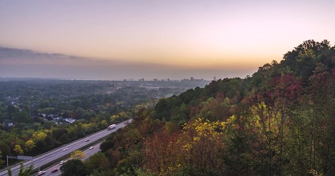 Sunrise time-lapse on top of Hamilton mountain facing the city of Hamilton Ontario, Canada and highway 403, with fall colored trees in the foreground.
