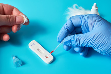 Express COVID-19 test for IgM and IgG antibodies to novel coronavirus SARS-CoV-2, Covid-19 viral pneumonia. Medics hand in glove holds the test. Vibrant blue mint and turquoise colors.