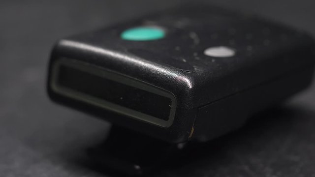 Dramatic Closeup of light illuminating an old retro vintage Pager Beeper in the dark while it passes over it 