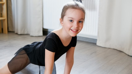 Little girl ballerina or gymnast engaged rehearsing at home movement - obrazy, fototapety, plakaty