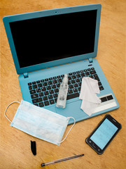 Blue laptop with surface disinfection kit on wooden table