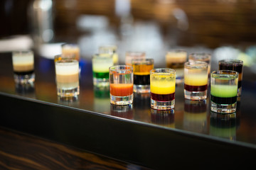 beautiful photo of many different alcoholic shots prepared by a bartender at the bar