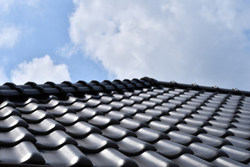 Fototapeta premium Close up of dark brown ceramic tile roof with blue sky background. Copy space. 