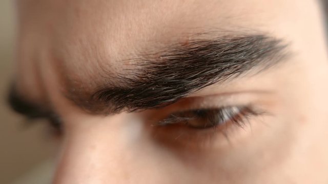 Macro closeup of man's eyes and eyebrows frowning, because he is being mad, upset , dissapointed