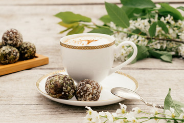 Сup of coffee and protein homemade sweets made from boiled lentils,cocoa powder, peanut paste, dates and decorated with nuts on a wooden background.Сoncept of healthy food and healthy desserts.