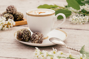 Сup of coffee and protein homemade sweets made from boiled lentils,cocoa powder, peanut paste, dates and decorated with nuts on a wooden background.Сoncept of healthy food and healthy desserts.
