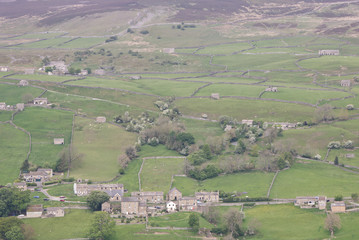 a Yorkshire Dales village with hills and fields surrounded by rock walls