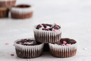 Homemade fresh chocolate chip muffins with sweet decorative pink and white hearts in white background.