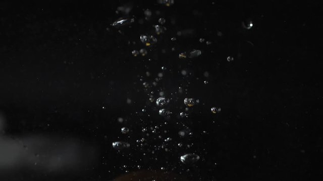 slice of orange falls into the water with bubbles, splashes and foam on a black background 180fps