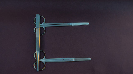 tijeras y pinzas quirúrgicas formando una letra c