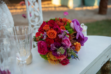 Bridal bouquet of red roses and orchids on a white table.