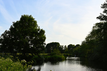 beautiful countryside river view with paddle boarders in the distance