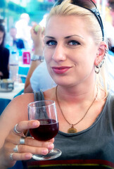 Young blonde caucasian woman enjoying a glass of red wine