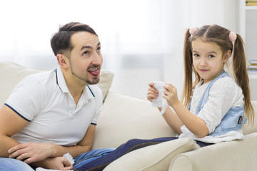 Father and his daughter are playing together at home.