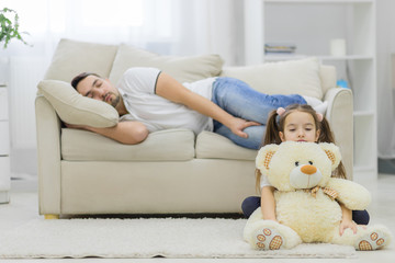 Dad is sleeping and his daughter sitting with white bear.