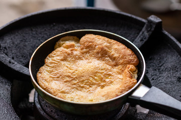 Fried omelette in a small pan on the old gas stove.