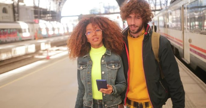 Young multi-ethnic couple using smartphone at train station