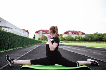 Healthy sports lifestyle. Athletic young woman in a sports dress doing fitness exercises. Fitness woman at the stadium. Young woman doing stretching. The young girl goes in for sports. Stretching.