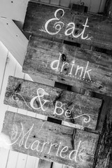 Sign at a wedding on rustic wood that says "Eat, Drink and Be Married"