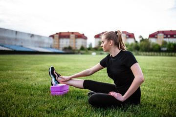 Healthy sports lifestyle. Athletic young woman in a sports dress doing fitness exercises. Fitness woman at the stadium. Young woman doing stretching. The young girl goes in for sports. Stretching. © Alex